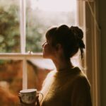 person drinking coffee cozy window morning