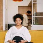 pregnant woman holding belly cozy living room