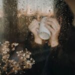 person sitting by window rainy day cozy