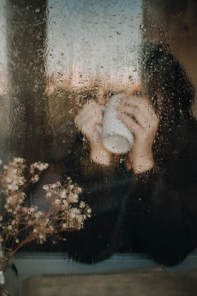 person sitting by window rainy day cozy