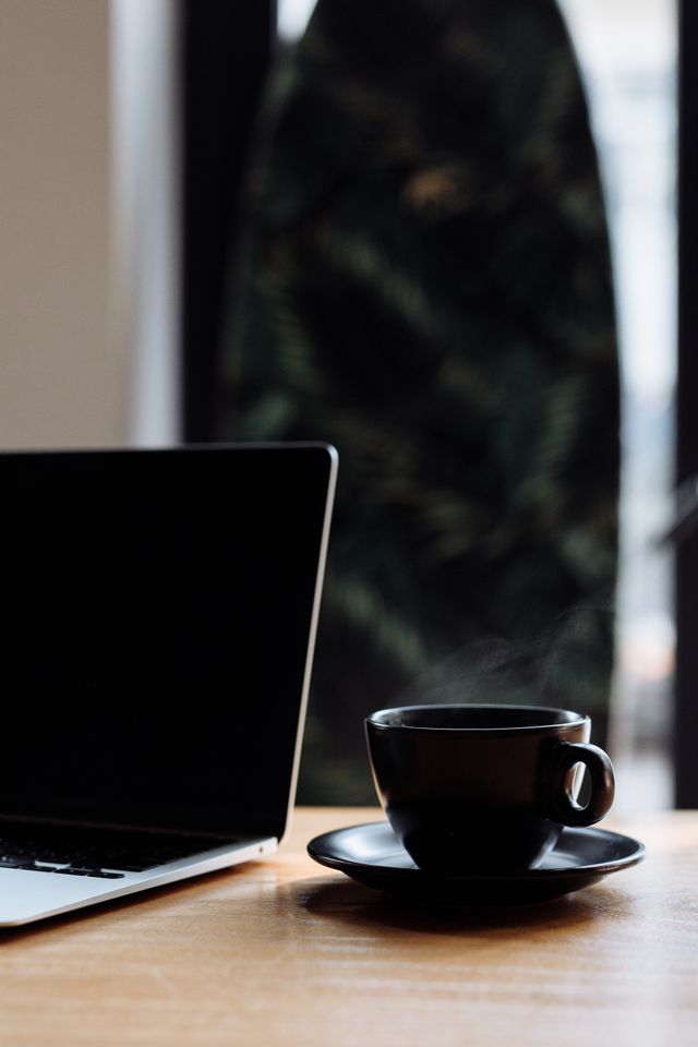 closed laptop coffee cup desk morning