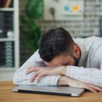 tired person working at desk laptop